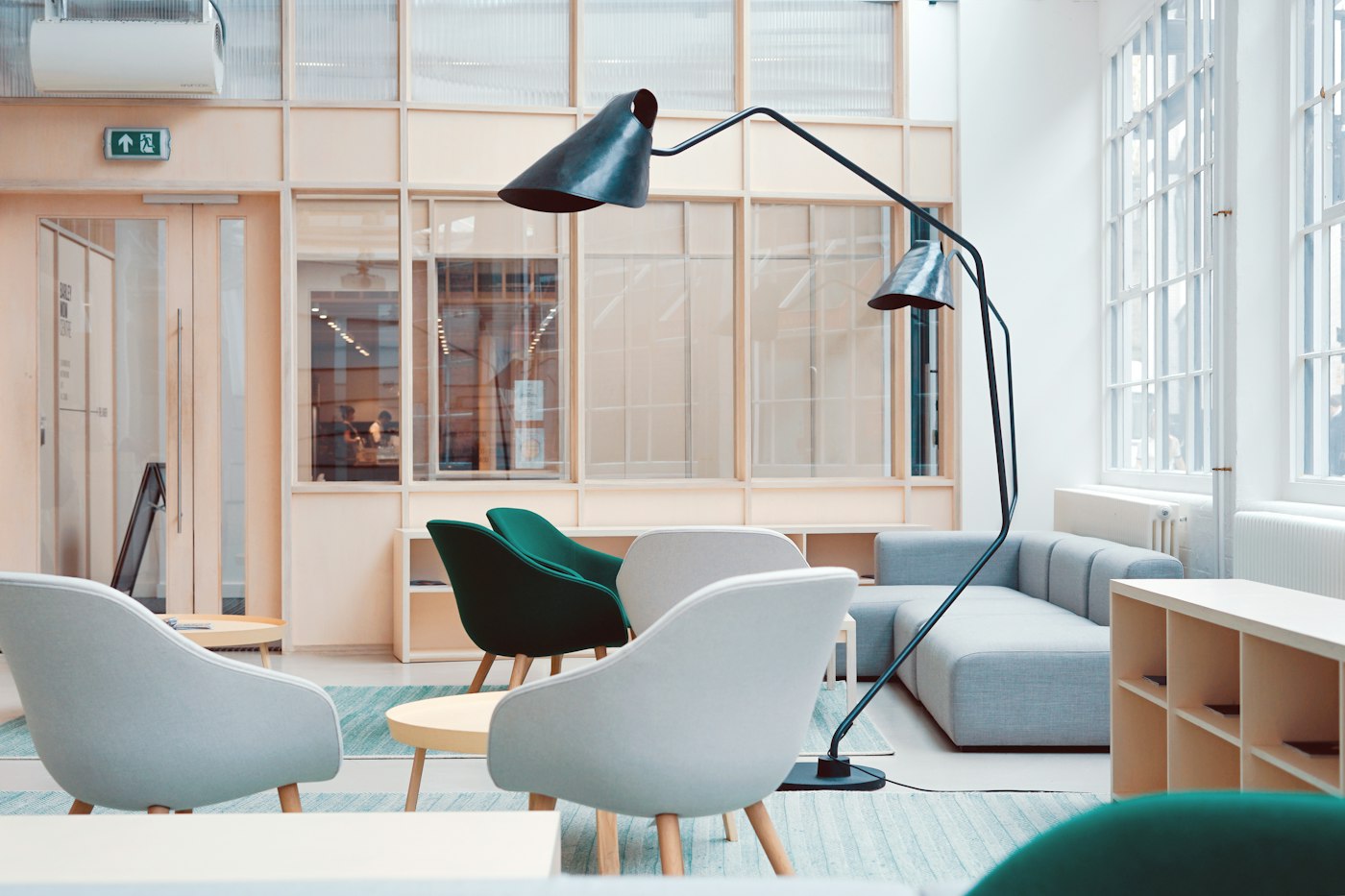 Workplace lounge with light wood partitions, soft seating and a large floor lamp
